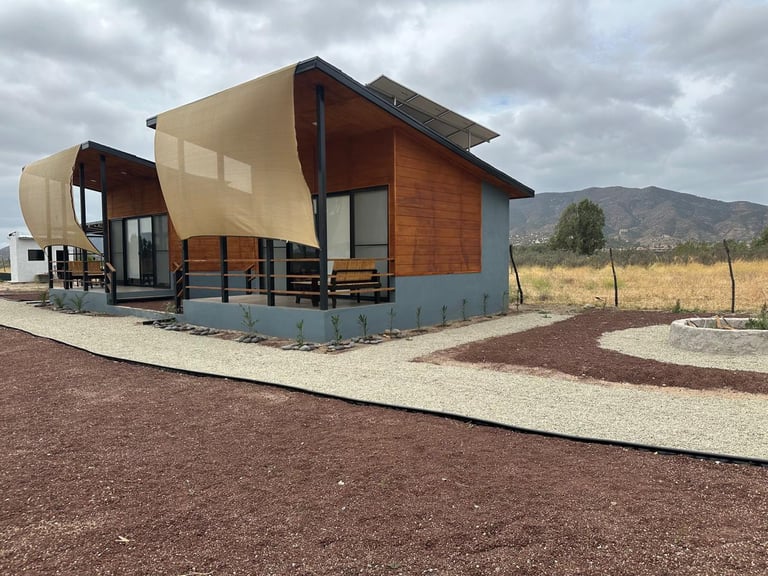Modern tiny house with curved metal roof and copper cladding in desert landscape with mountains in background